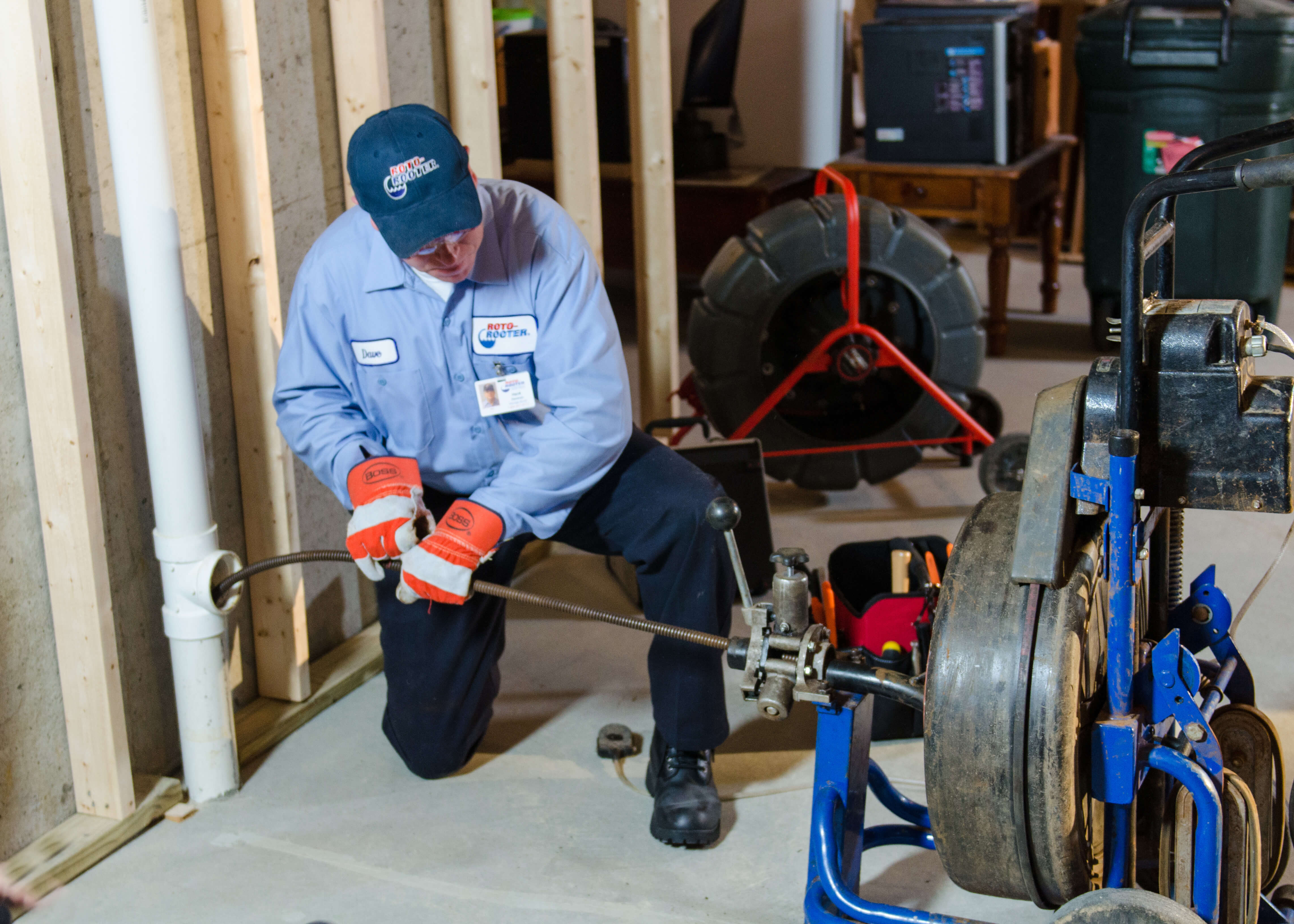 Roto-Rooter plumber using patented drain cleaning machine to clear drains via basement pipes