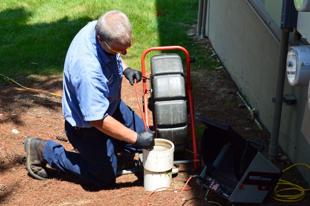 Plumber outside using waterproof video camera snake to complete a visual inspection of sewer lines