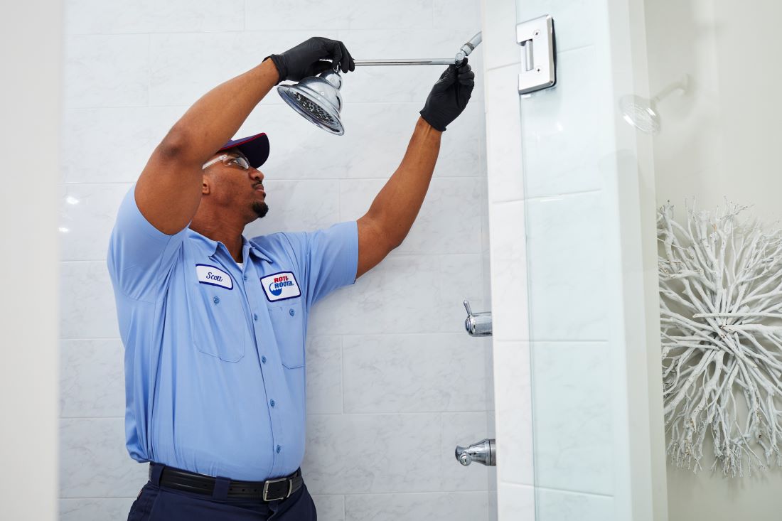 Plumber removing showerhead in customer bathroom