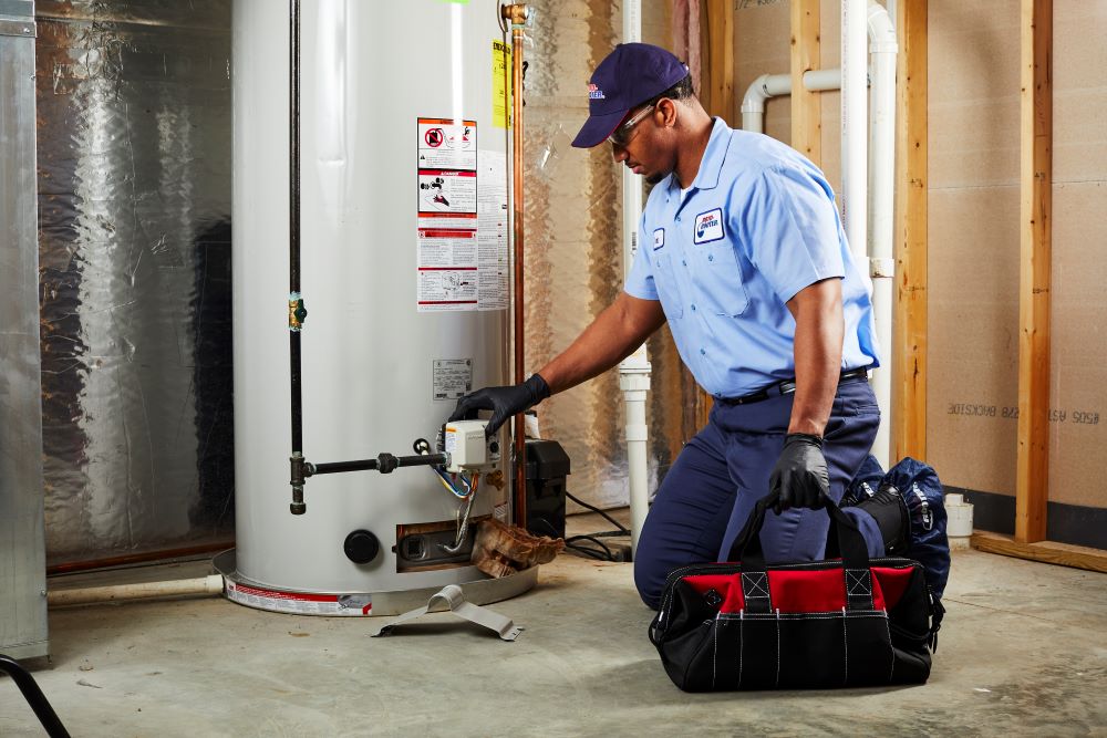 Plumber with tool bag evaluating gas water heater gas control valve