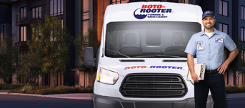 Smiling Roto-Rooter plumber with service van ready for work