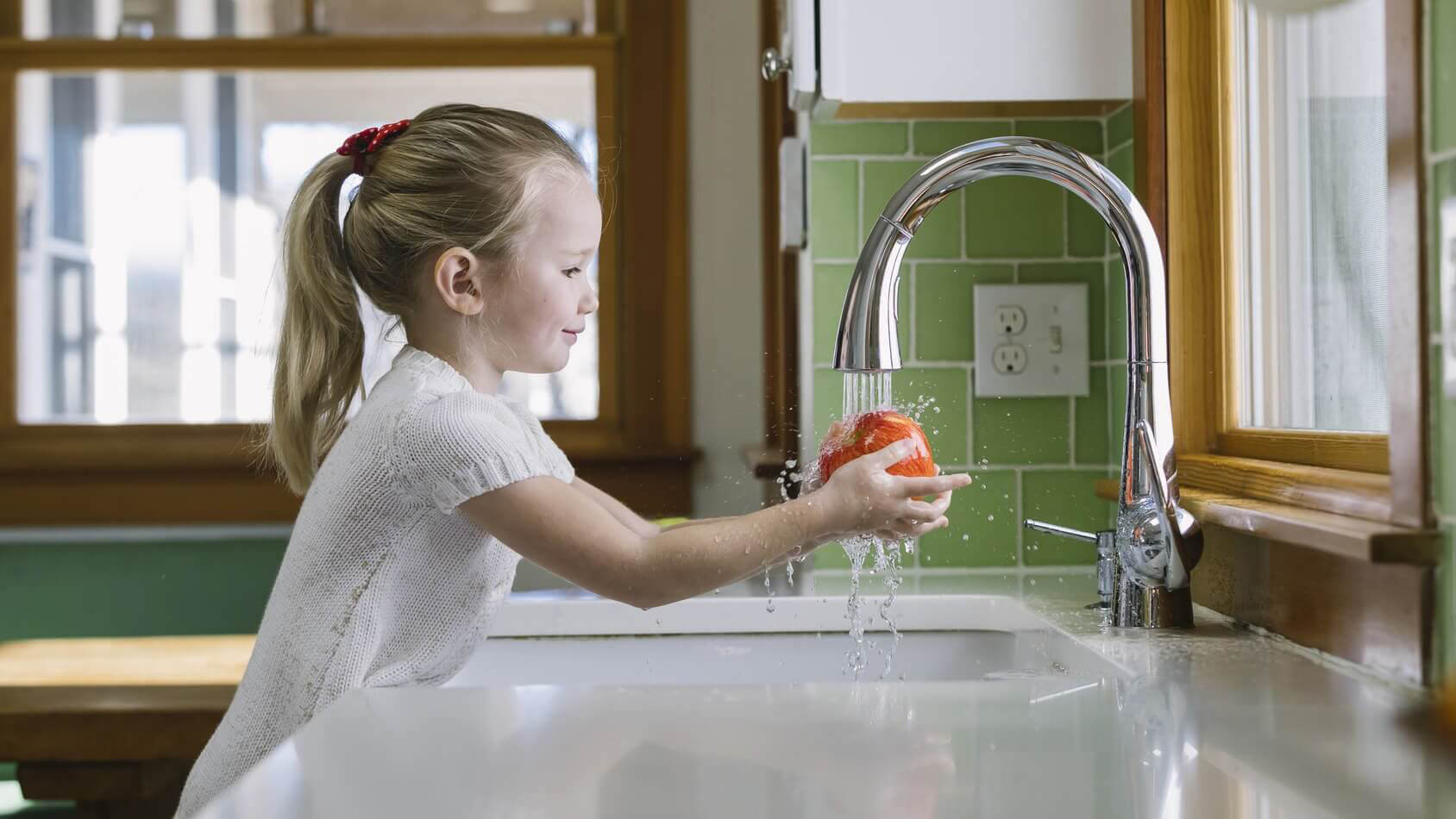Girl washing apples in sink